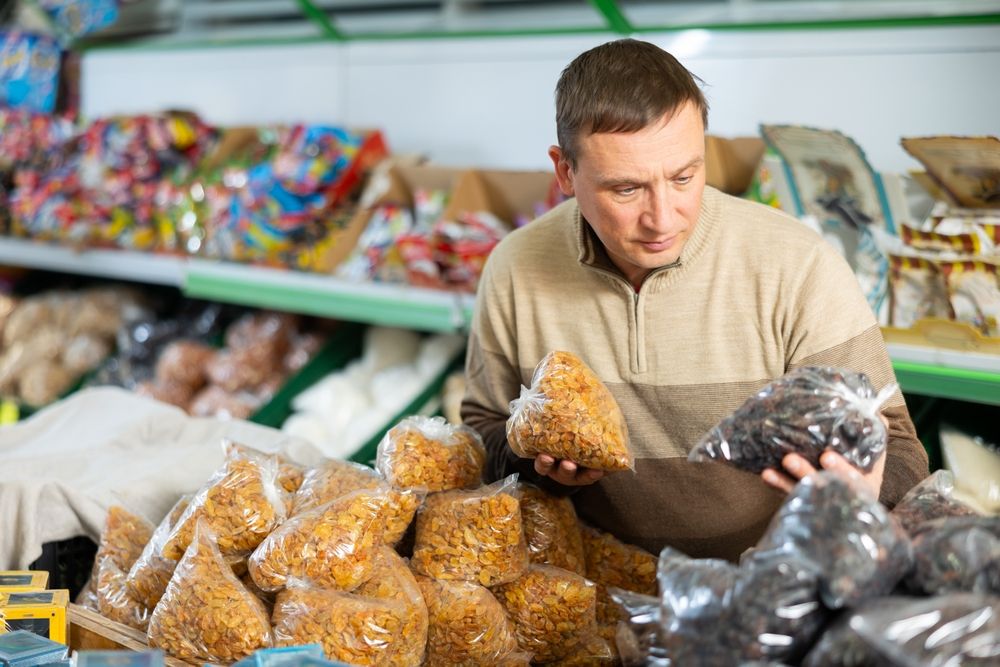 Thinking,Man,Stands,In,Department,Of,Supermarket,And,Chooses,Packaged