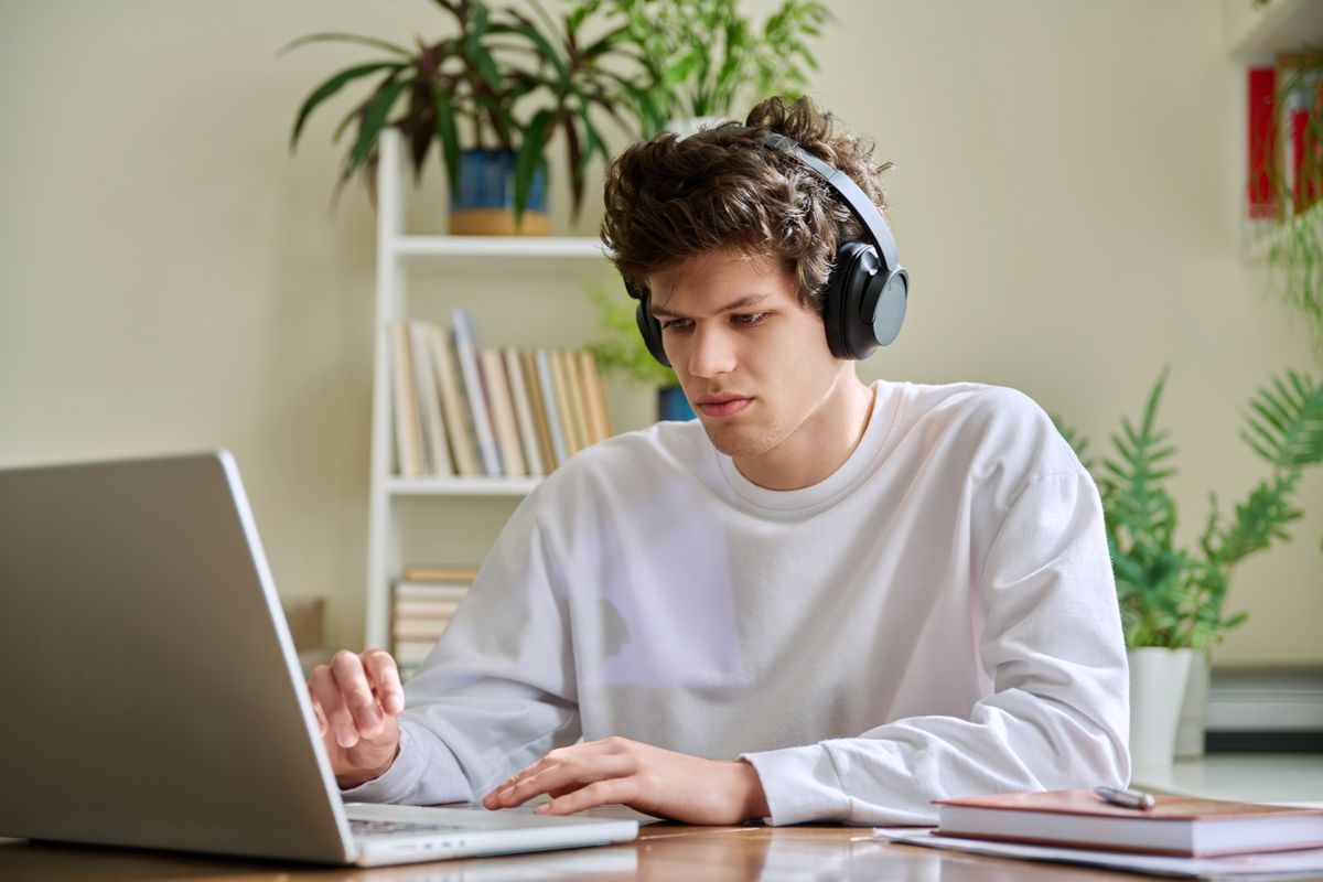 Young,Male,College,Student,In,Headphones,Sitting,At,Desk,At