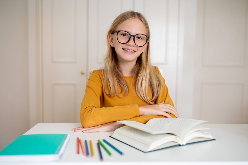 Nerdy,Teenage,Girl,Wearing,Glasses,Sitting,At,Her,Desk,With