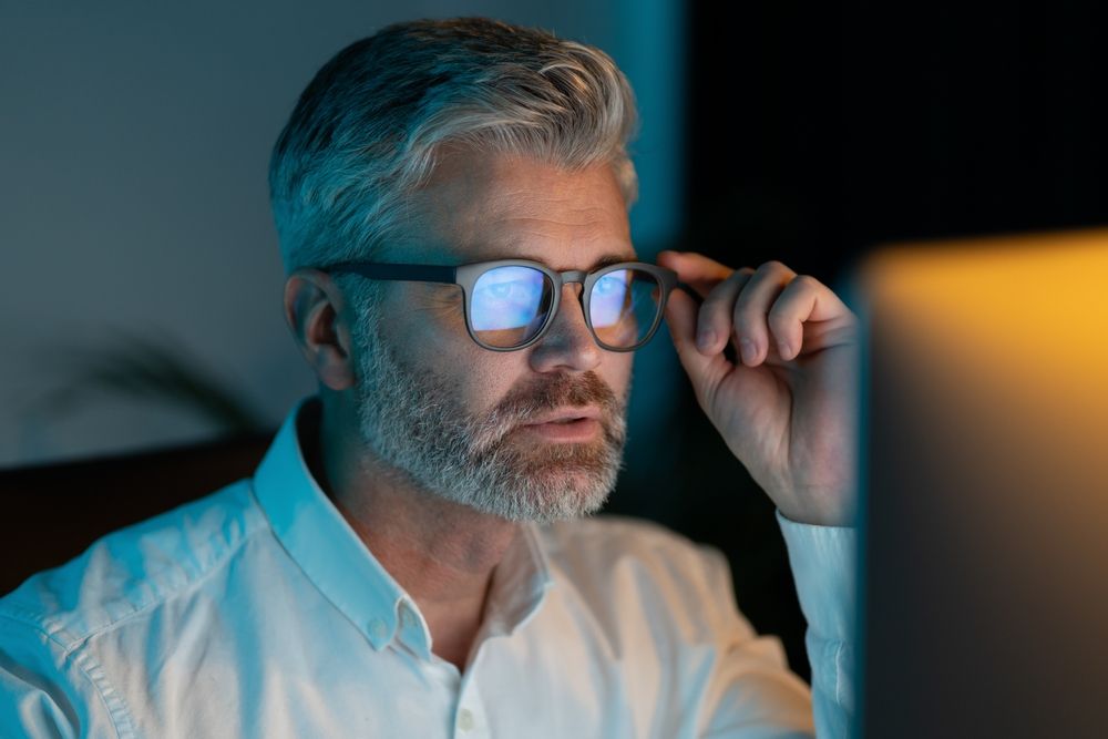 Focused,Mature,Man,Wearing,Glasses,Working,On,Computer,At,Night